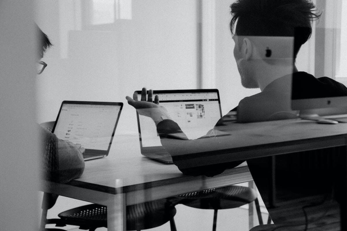 Two people on laptops at a table discussing an effective enterprise search strategy.